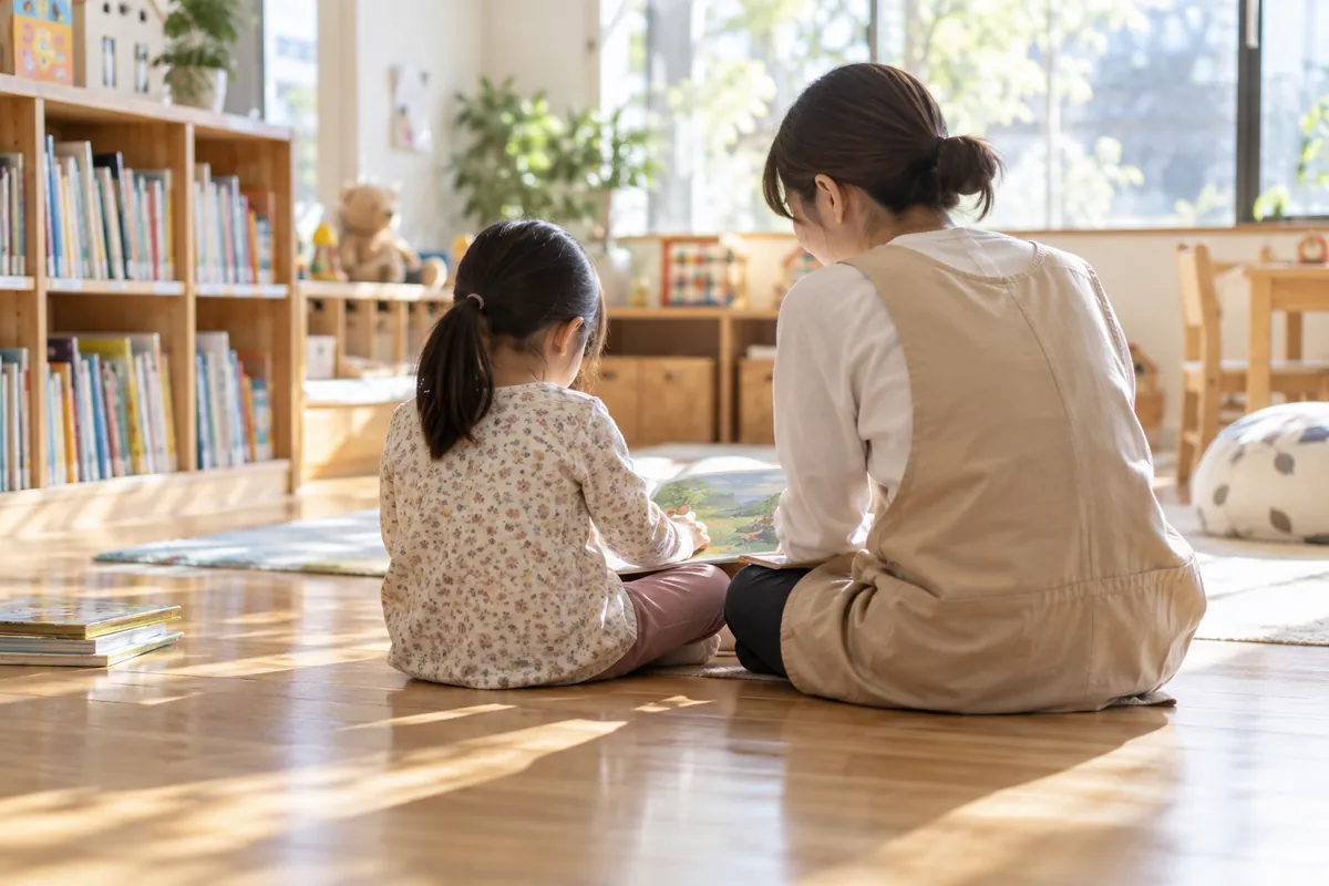 本棚のある部屋で、床に並んで座る子どもとスタッフの後ろ姿